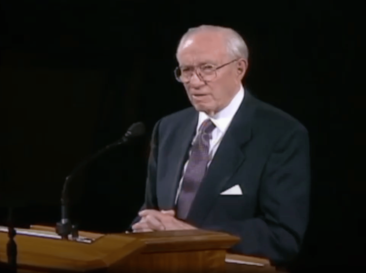 Uma captura de uma transmissão em vídeo mostrando o Presidente Gordon B. Hinckley no púlpito, diante de um fundo preto, lendo a Proclamação da Família pela primeira vez como parte de sua mensagem na reunião geral da Sociedade de Socorro realizada em 23 de setembro de 1995, em Salt Lake City, Utah.