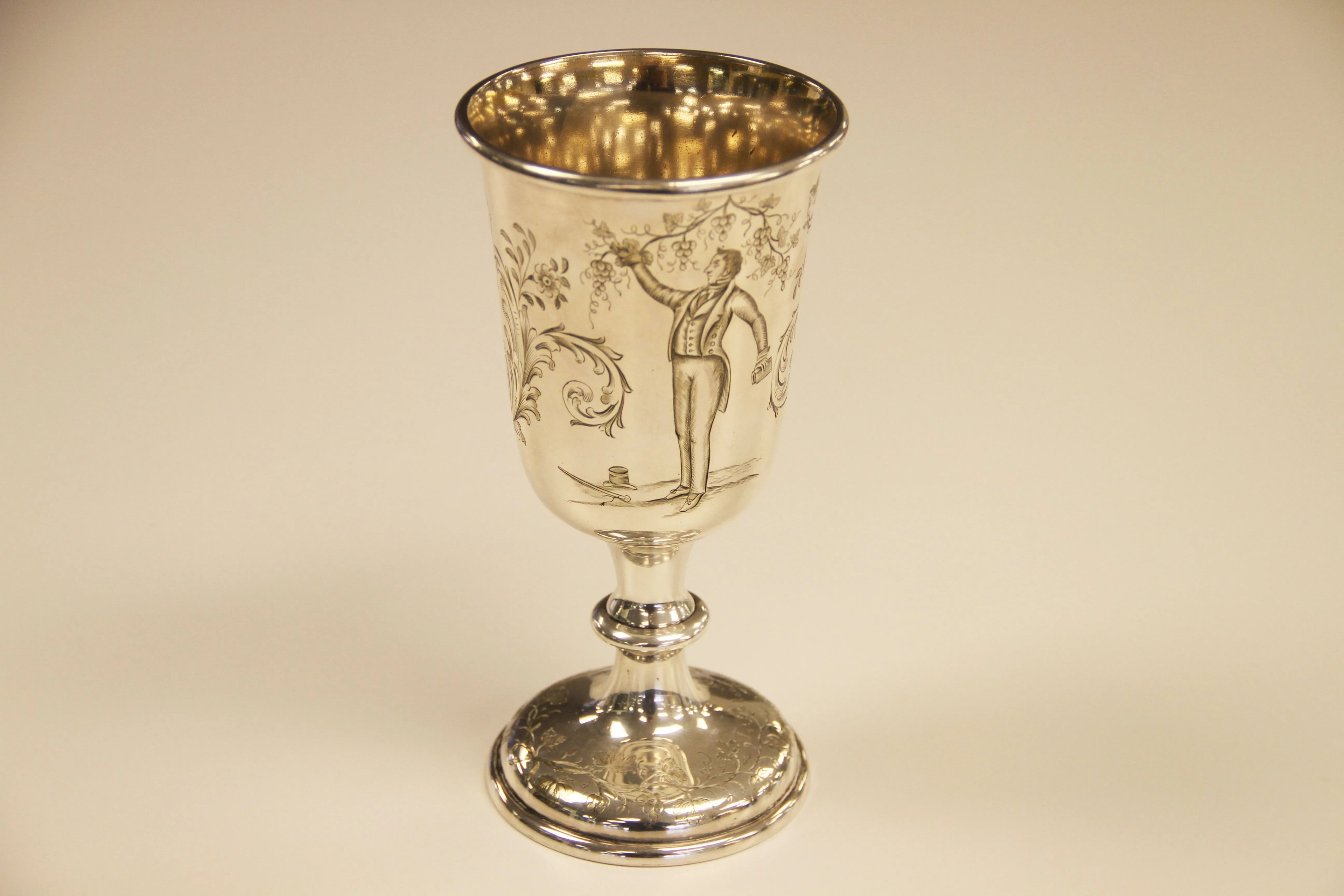 Un'immagine di un calice d'argento del 1847 su uno sfondo semplice, usato nelle riunioni sacramentali dei Santi degli Ultimi Giorni o dei Mormoni, con un'immagine incisa di Joseph Smith tra tralci di vite.