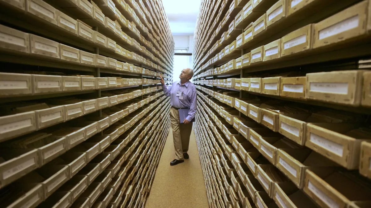 Een man, Gary Mokotoff, een Joodse genealoog, bekijkt naamregisters tussen een groot aantal planken in Duitsland, 2008.