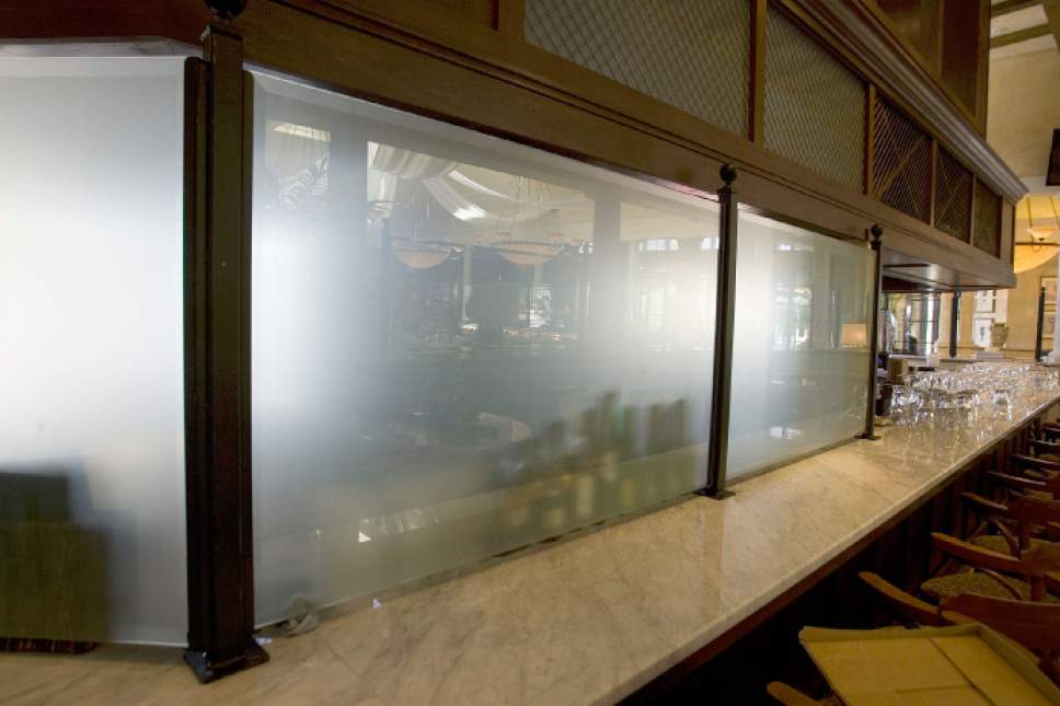 Une photo d’un bar avec un rideau de Sion, une grande barrière en verre translucide destinée à empêcher les clients de voir les boissons être préparées.